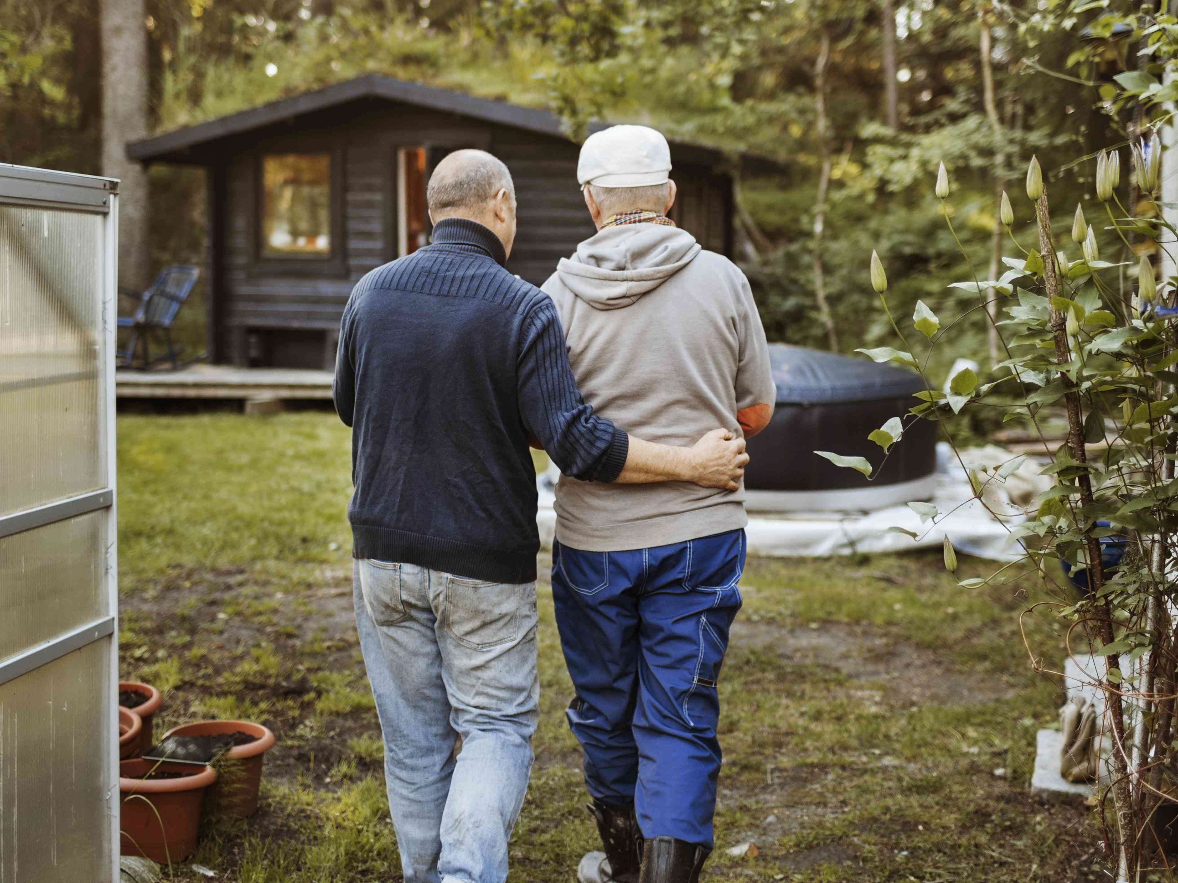 Older gay couple walking to a cabin in the countryside
