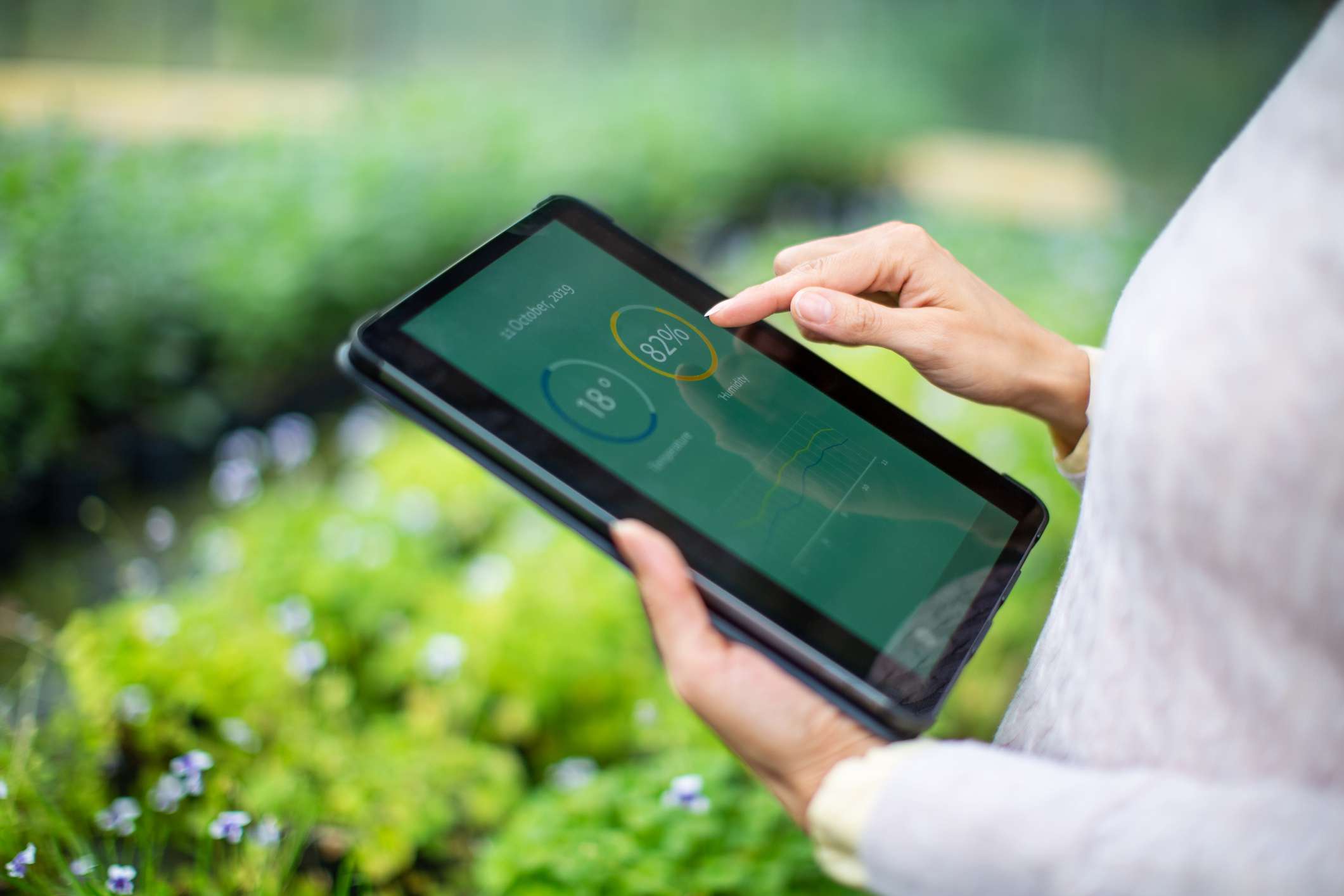midsection of a person using a tablet that has data on it in a garden