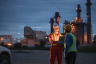 Two people standing in front of an oil and gas refinery.