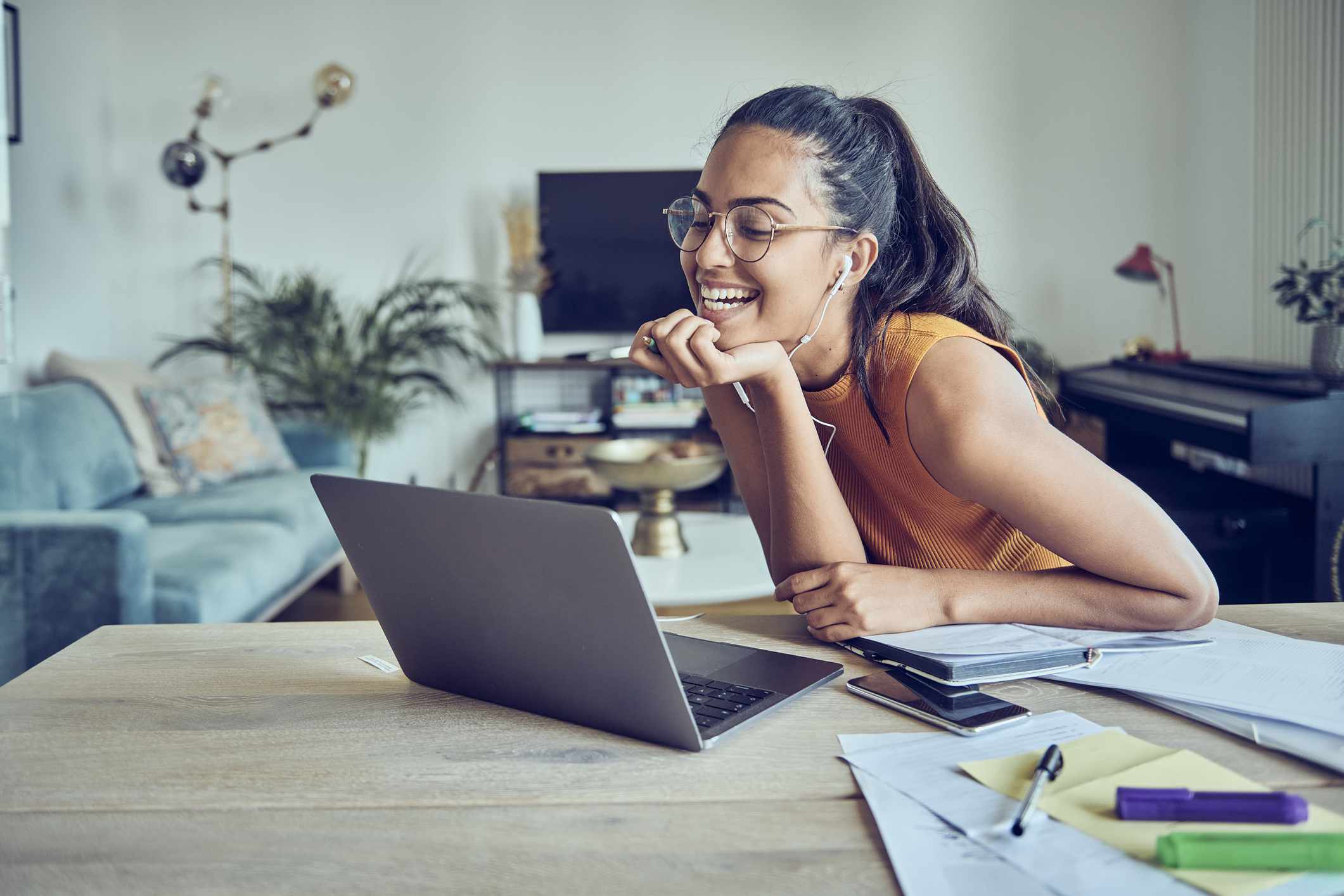 Young woman smiling and working at home on her laptop