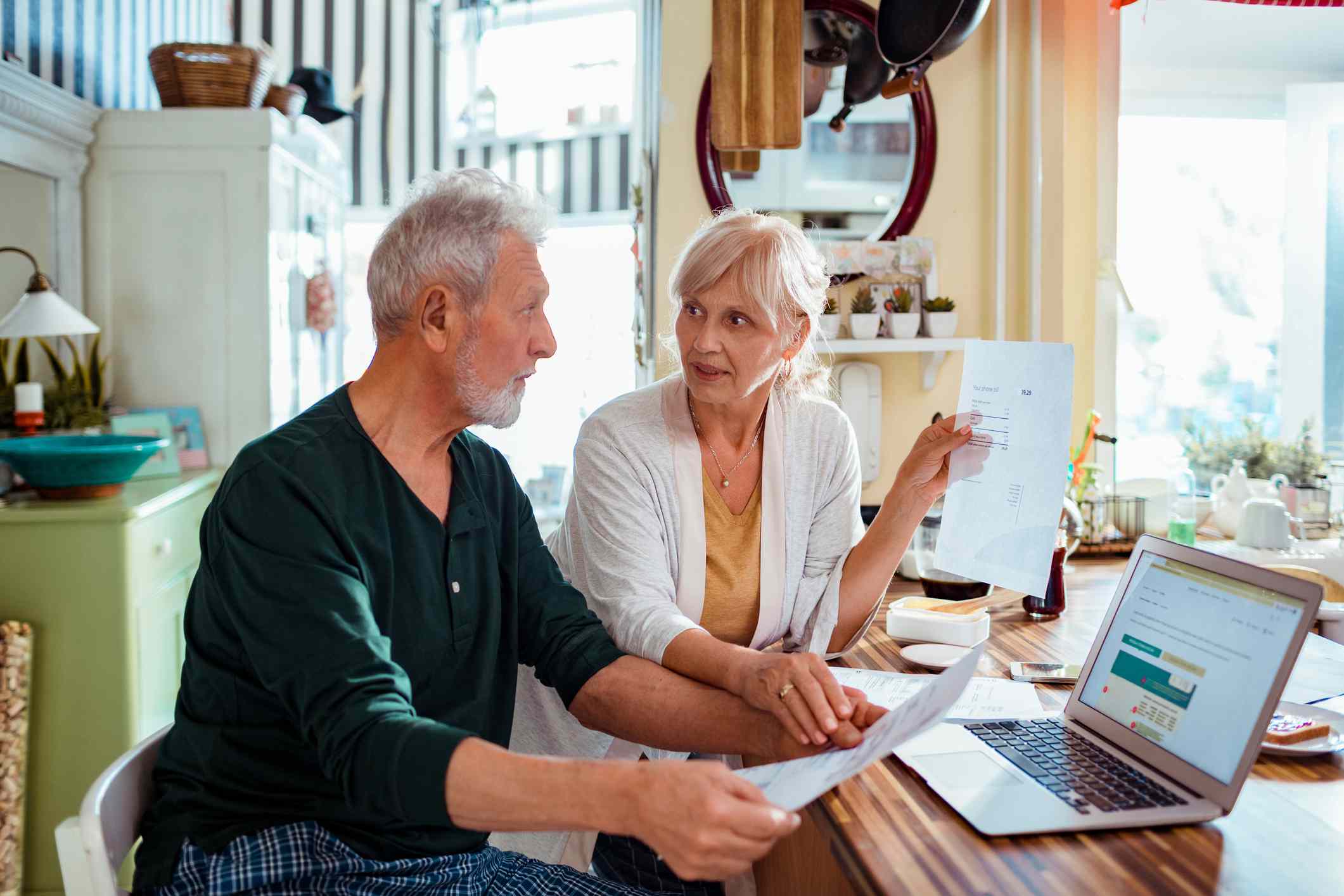 Couple reviews retirement plans at home using laptop