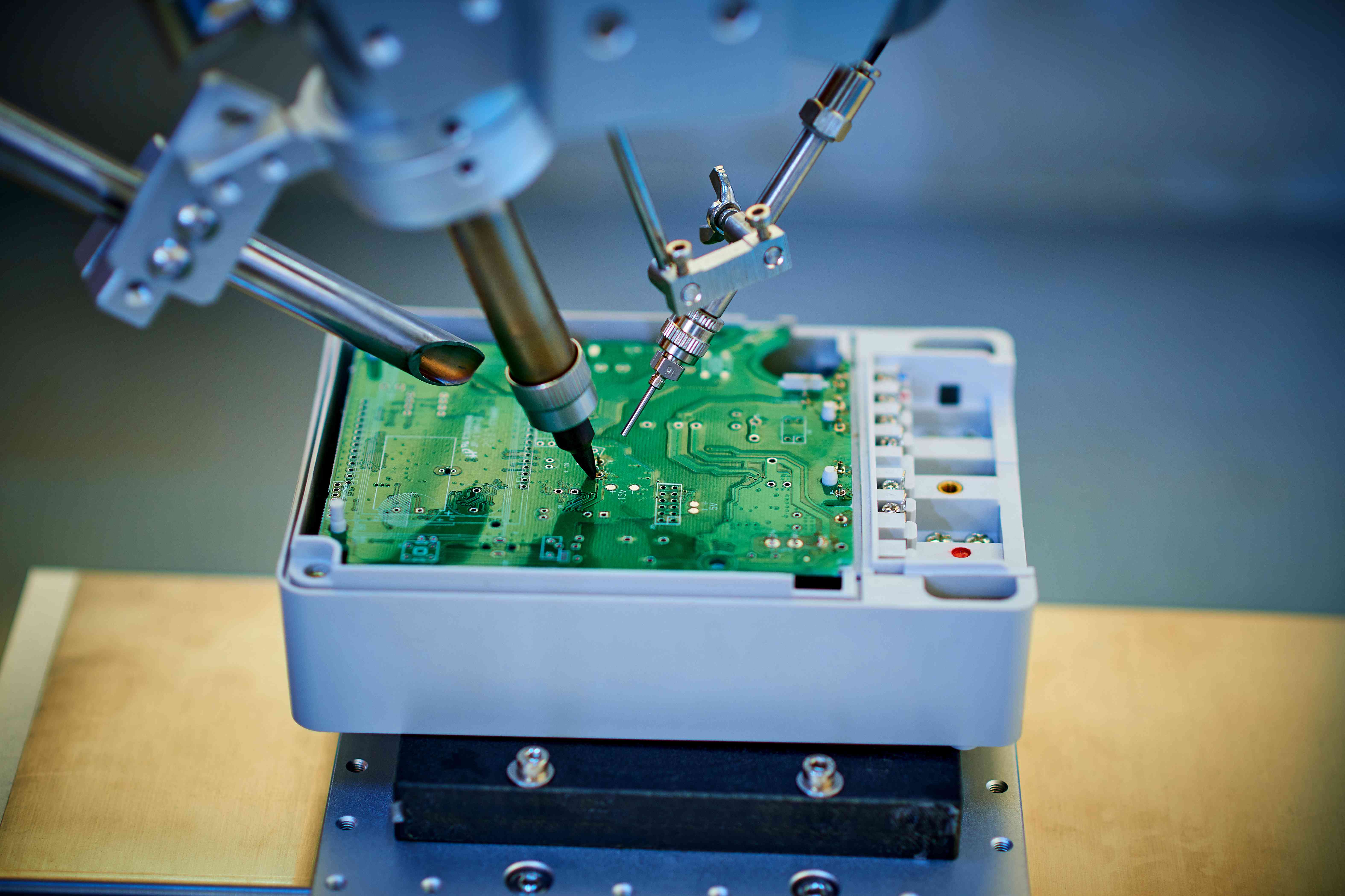 Robotic arm welding and installing component at semiconductor circuit board on workbench
