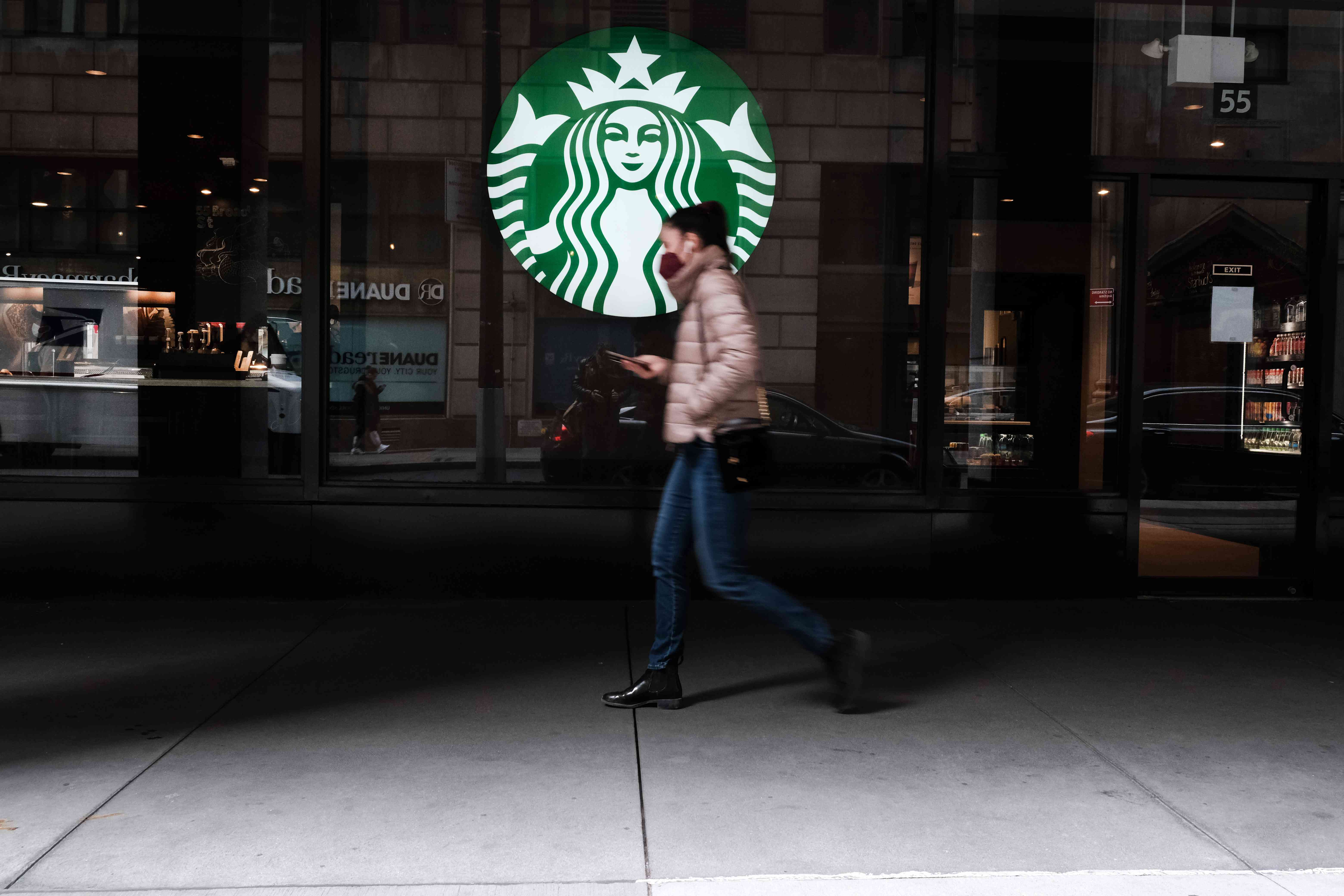 A woman walks by a Starbucks coffee shop in Manhattan on April 04, 2022 in New York City.