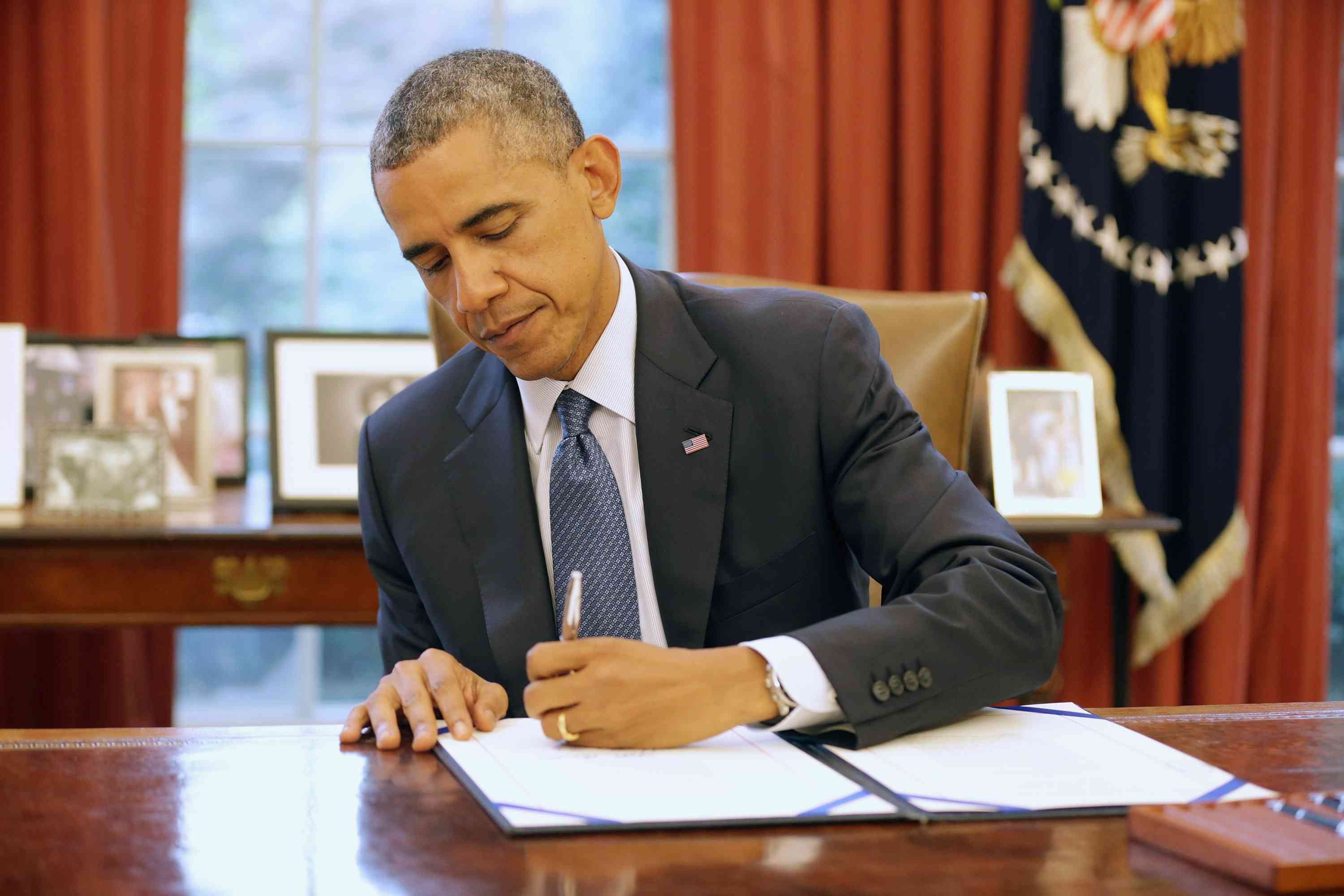 President Barack Obama signing bill in Oval Office.