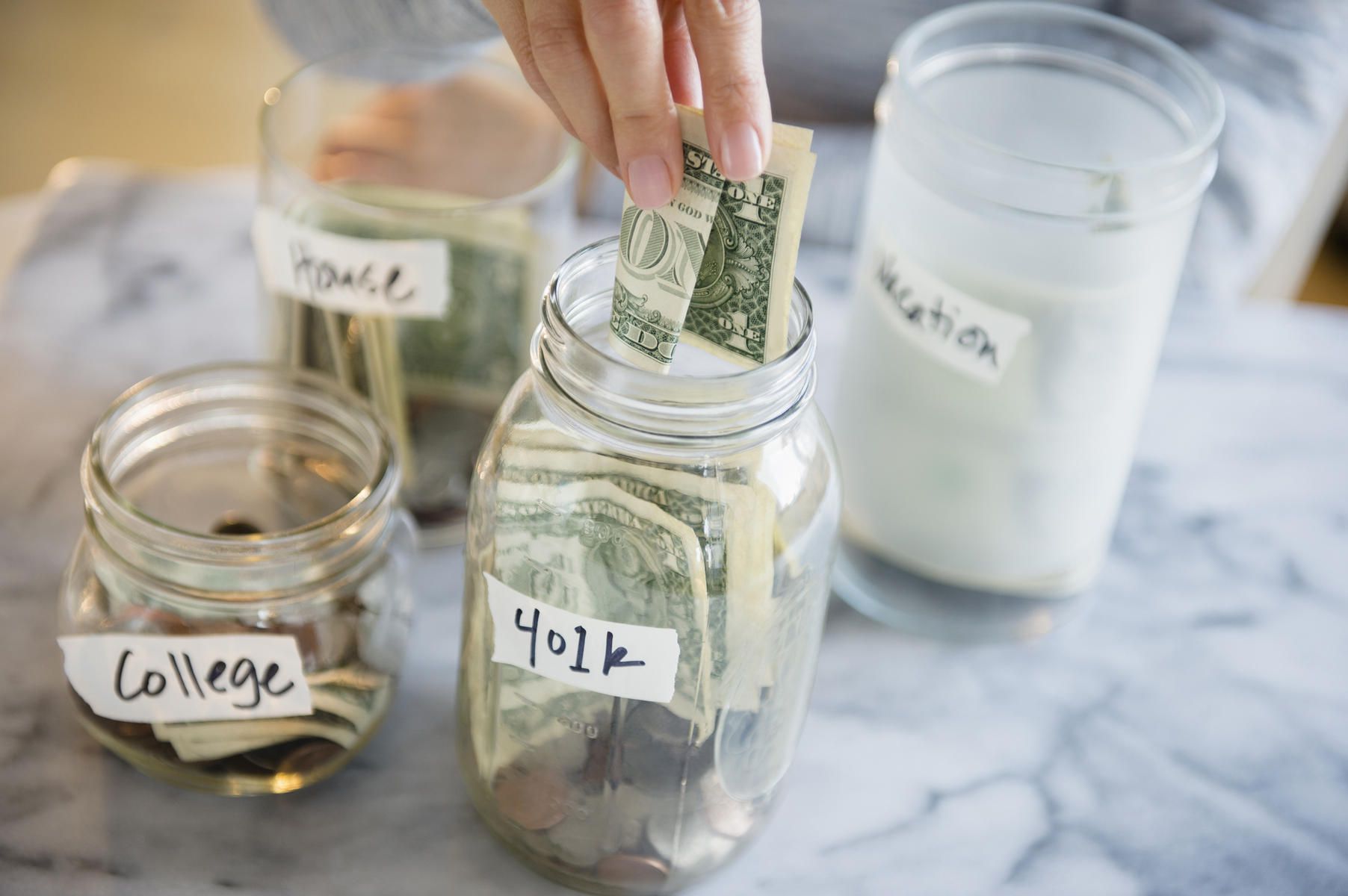 Woman saving money for college and retirement in jars