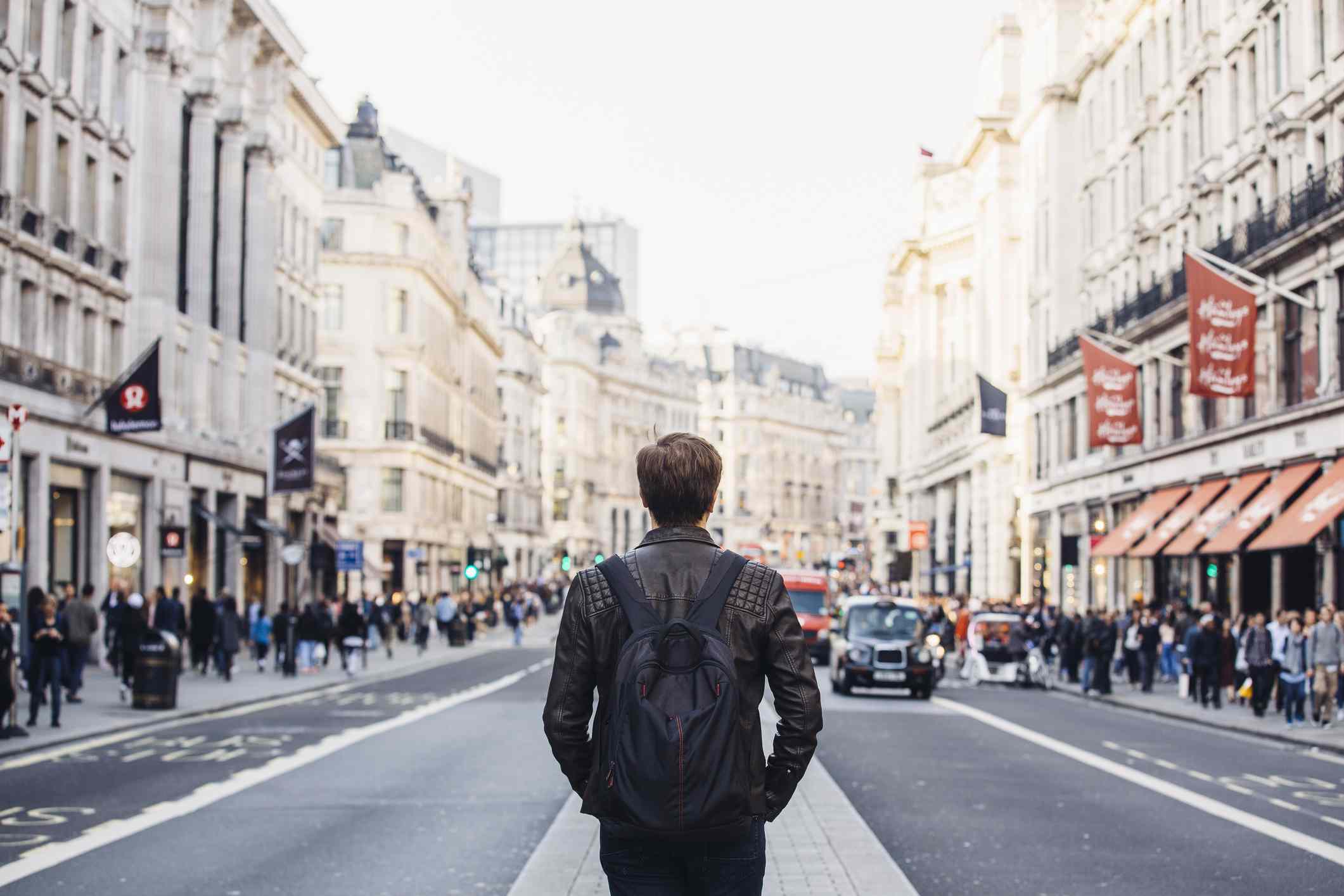 Tourist with backpack walking on Regent Street in London, UK.