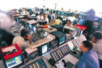 People in shirtsleeves sit at trading desks in a large room