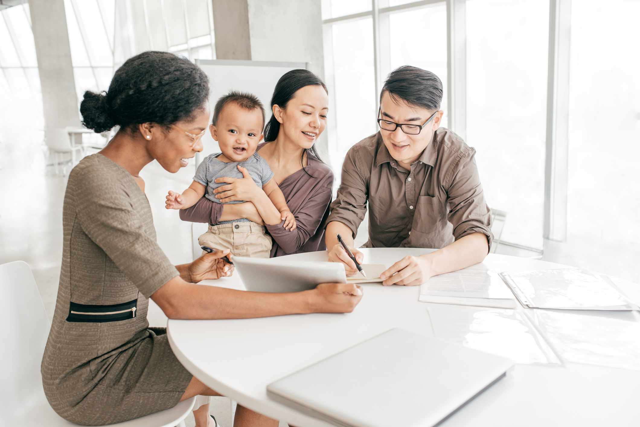 Couple with baby at a table signing paperwork with a mortgage lender