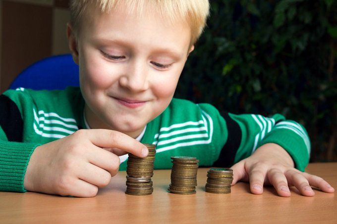 Little boy with 3 piles of coins