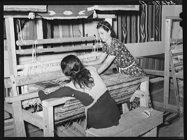 A Works Progress Administration supervisor teaches a woman how to weave a rug.